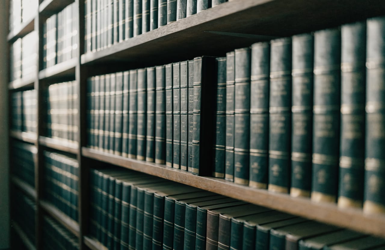 Wooden shelf filled with bound volumes of legislation, one volume pulled forward